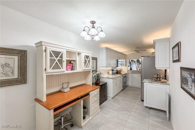 kitchen featuring appliances with stainless steel finishes, ceiling fan with notable chandelier, a textured ceiling, and light tile patterned floors