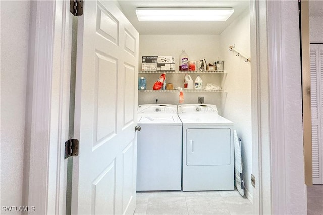 clothes washing area with washing machine and dryer and light tile patterned floors