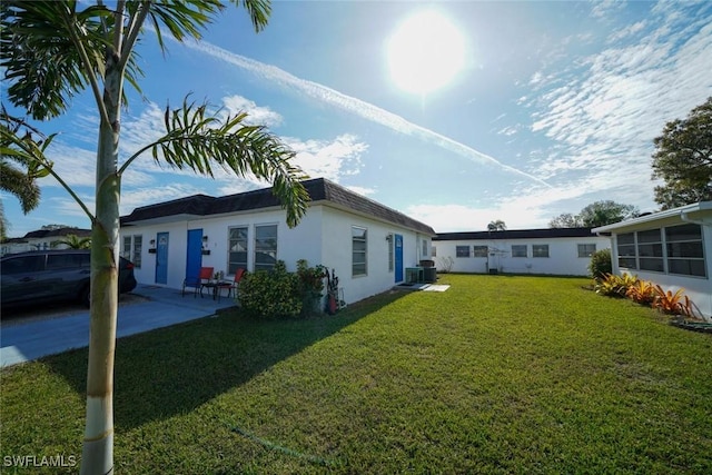 rear view of house with a patio area, a yard, and central AC