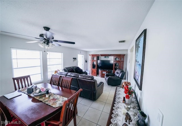 tiled dining area with a textured ceiling and ceiling fan