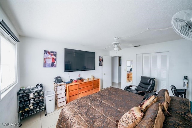 bedroom featuring a textured ceiling, a closet, ceiling fan, and light tile patterned flooring