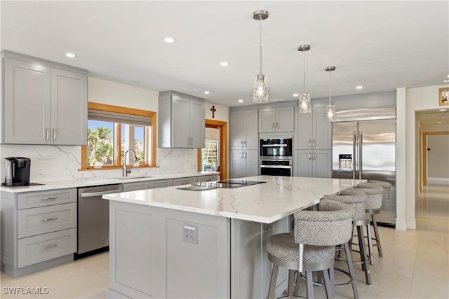 kitchen with gray cabinetry, a center island, sink, hanging light fixtures, and stainless steel appliances