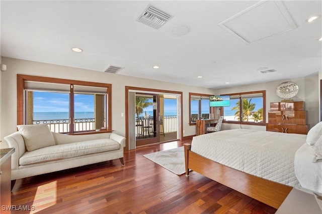 bedroom featuring access to exterior, dark hardwood / wood-style flooring, and a water view