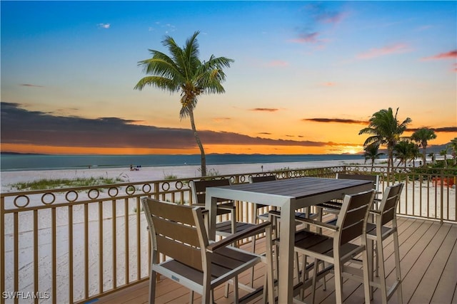 deck at dusk featuring a water view