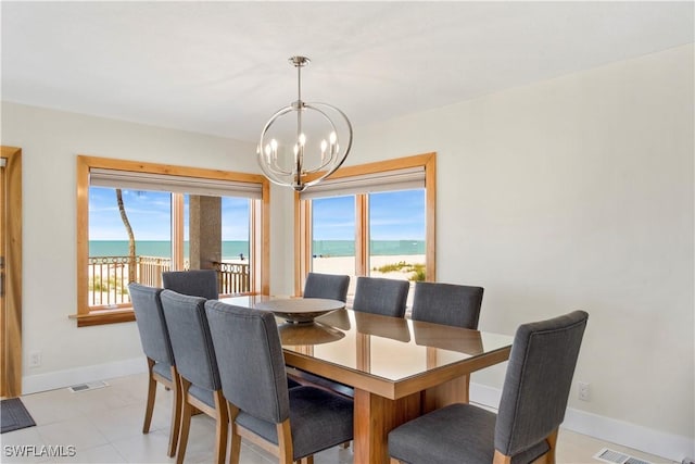 dining area featuring a water view, a notable chandelier, and light tile patterned flooring