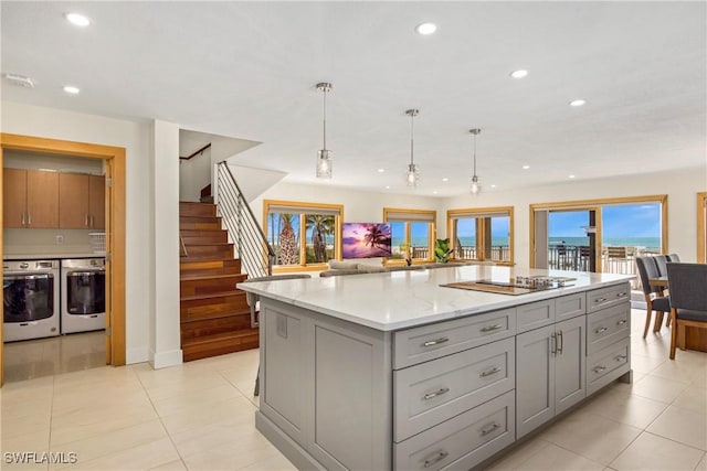 kitchen with pendant lighting, black electric stovetop, gray cabinets, light stone countertops, and a kitchen island