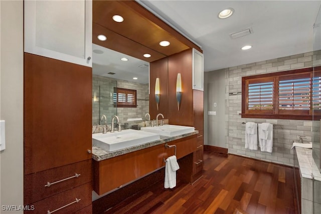 bathroom with hardwood / wood-style floors, vanity, tile walls, and a washtub