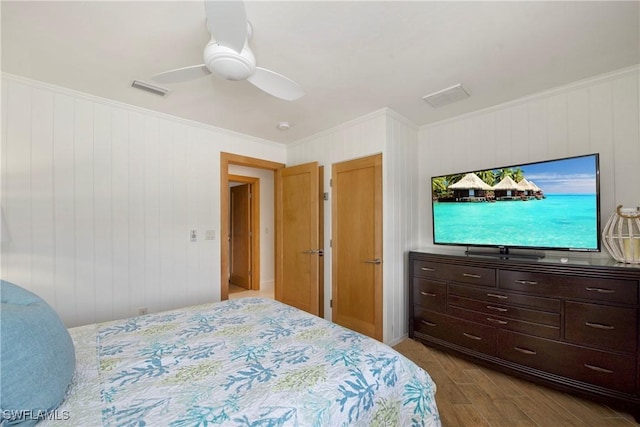 bedroom with light wood-type flooring, wooden walls, ceiling fan, and crown molding