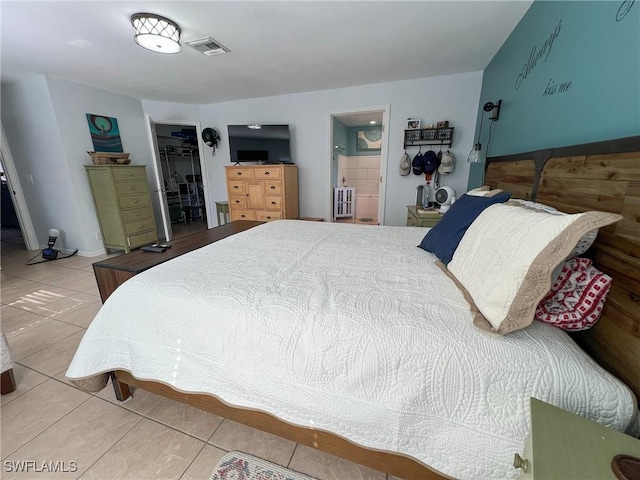 tiled bedroom featuring ensuite bathroom, a spacious closet, and a closet