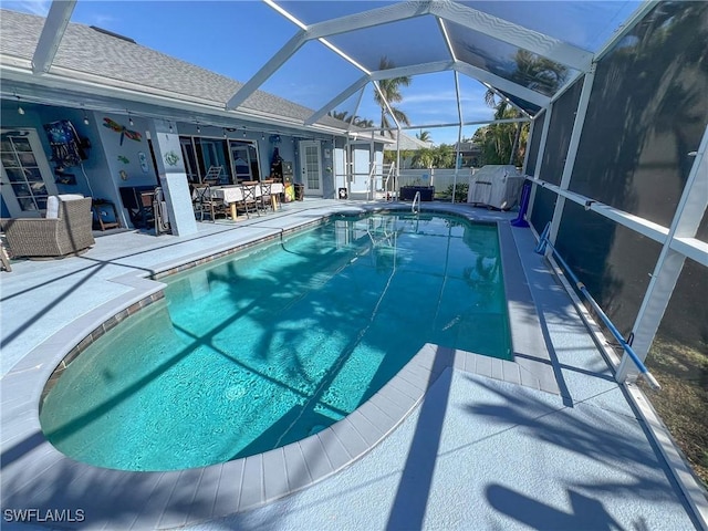 view of pool with a patio, glass enclosure, and a storage unit