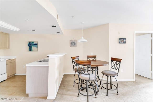 kitchen featuring pendant lighting, light brown cabinets, white range, and light carpet