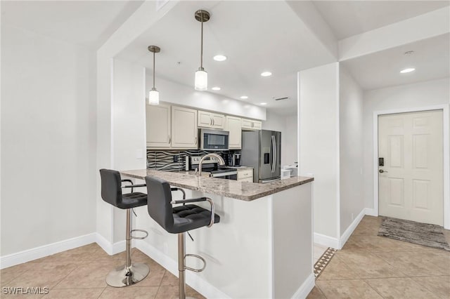 kitchen featuring pendant lighting, light tile patterned floors, stainless steel appliances, and stone countertops