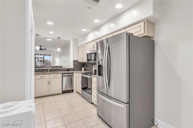 kitchen featuring appliances with stainless steel finishes, backsplash, sink, light tile patterned floors, and hanging light fixtures