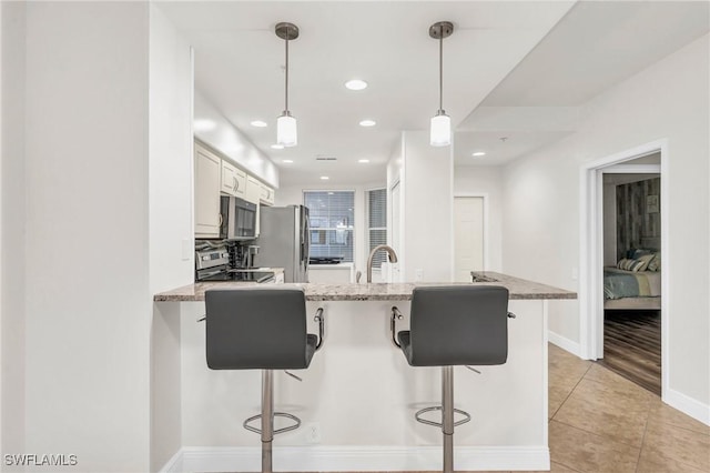 kitchen with kitchen peninsula, a breakfast bar, stainless steel appliances, white cabinets, and hanging light fixtures