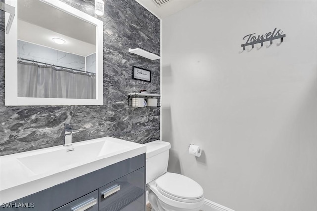 bathroom featuring walk in shower, vanity, tile walls, and toilet