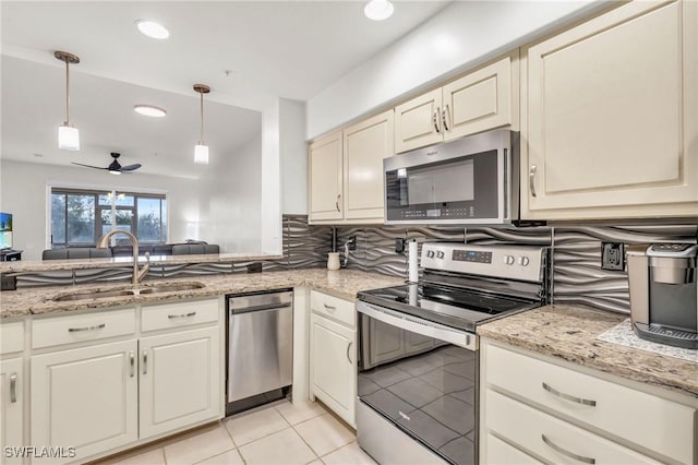 kitchen with backsplash, sink, ceiling fan, appliances with stainless steel finishes, and decorative light fixtures