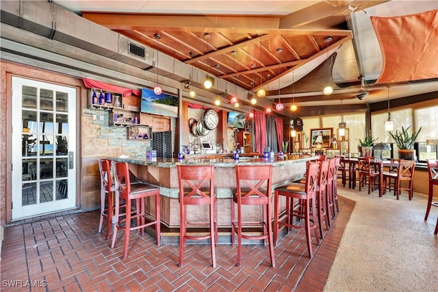 bar with vaulted ceiling with beams, stone countertops, and decorative light fixtures