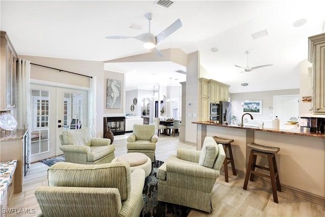 living room with ceiling fan, french doors, vaulted ceiling, light hardwood / wood-style flooring, and sink