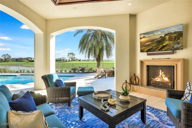 view of patio / terrace with an outdoor living space with a fireplace, a fenced in pool, and a water view