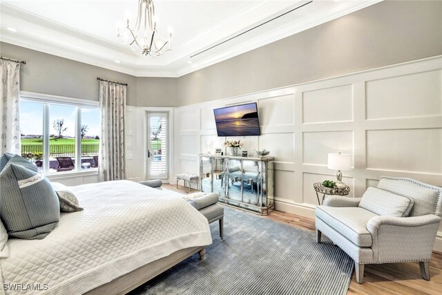 bedroom featuring hardwood / wood-style flooring, a notable chandelier, crown molding, and a tray ceiling