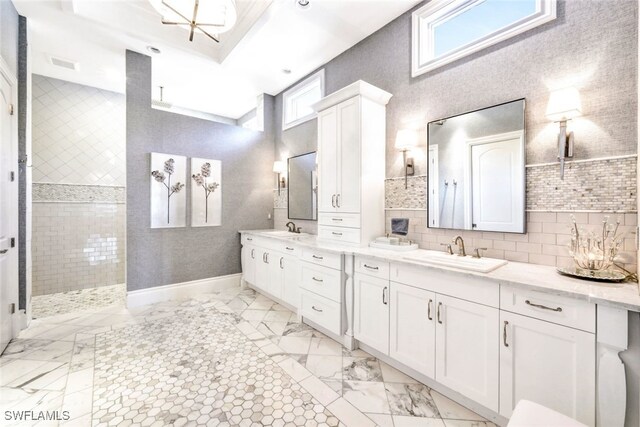 bathroom featuring decorative backsplash, a healthy amount of sunlight, a tile shower, and vanity