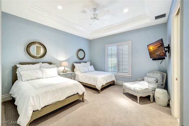 carpeted bedroom with a tray ceiling and ceiling fan