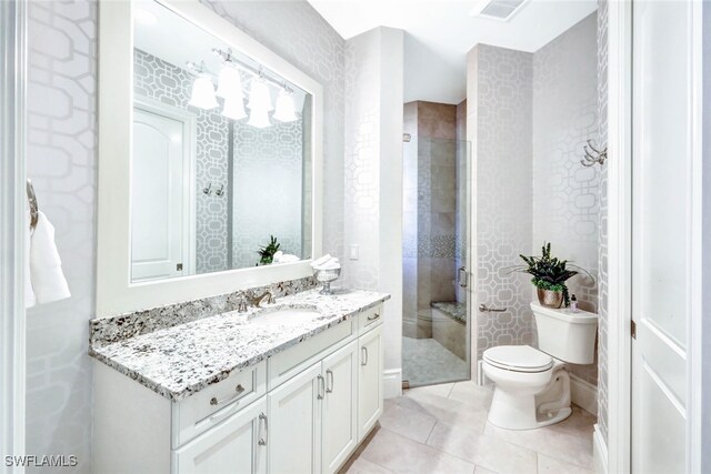 bathroom with tile patterned floors, vanity, toilet, and an enclosed shower