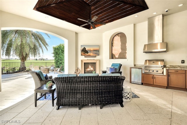 view of patio with an outdoor living space with a fireplace, grilling area, exterior kitchen, and ceiling fan