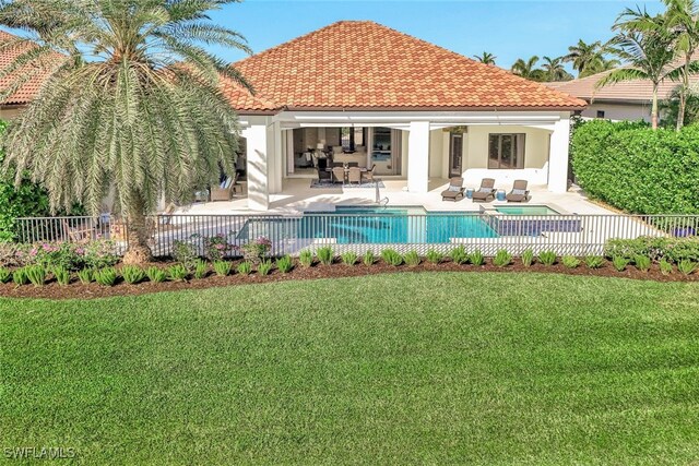 back of property with a fenced in pool, a patio area, and a lawn