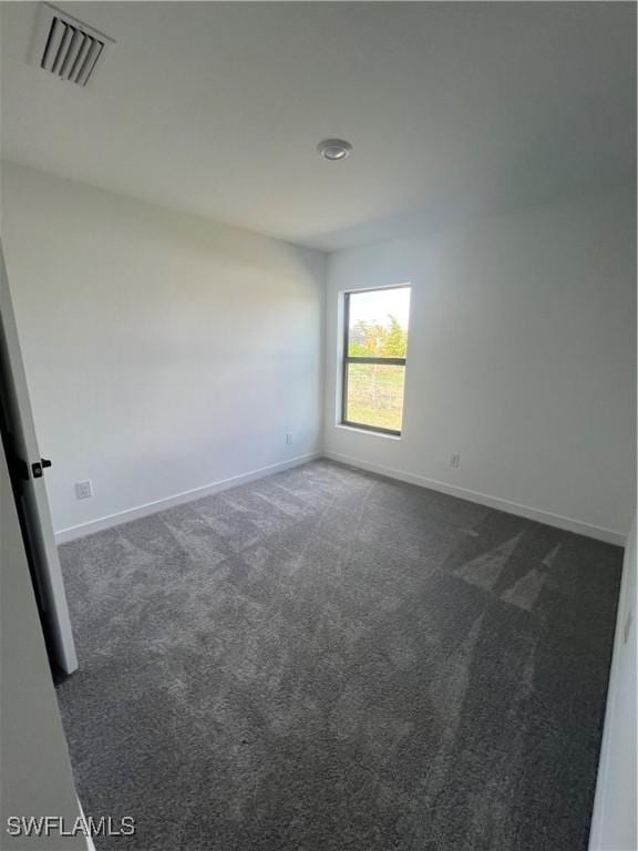 unfurnished room featuring dark colored carpet