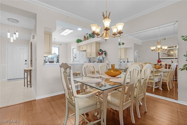 dining room with light hardwood / wood-style floors, crown molding, and an inviting chandelier