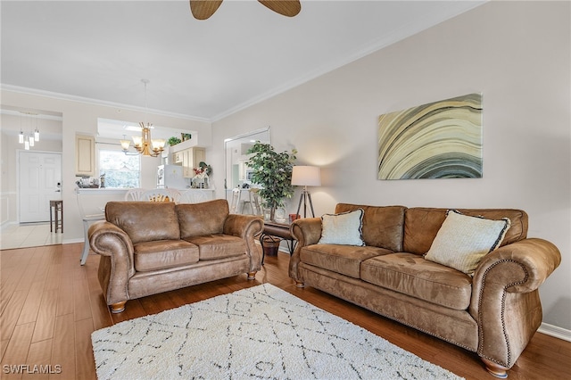 living room featuring hardwood / wood-style floors, ceiling fan with notable chandelier, and ornamental molding