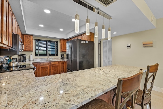 kitchen with sink, stainless steel appliances, a raised ceiling, kitchen peninsula, and decorative light fixtures