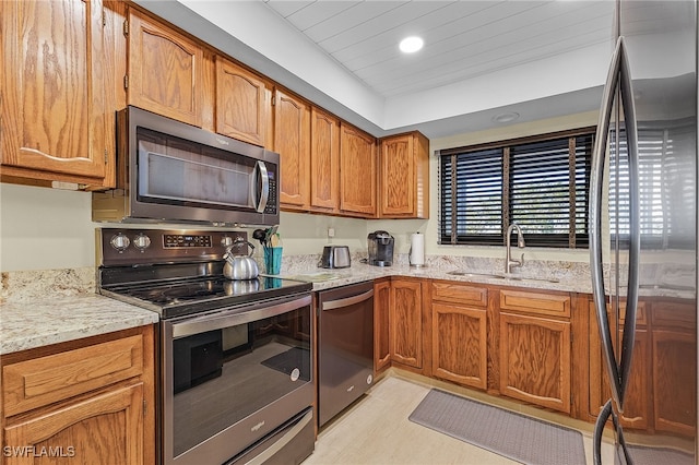 kitchen featuring appliances with stainless steel finishes, light stone counters, and sink