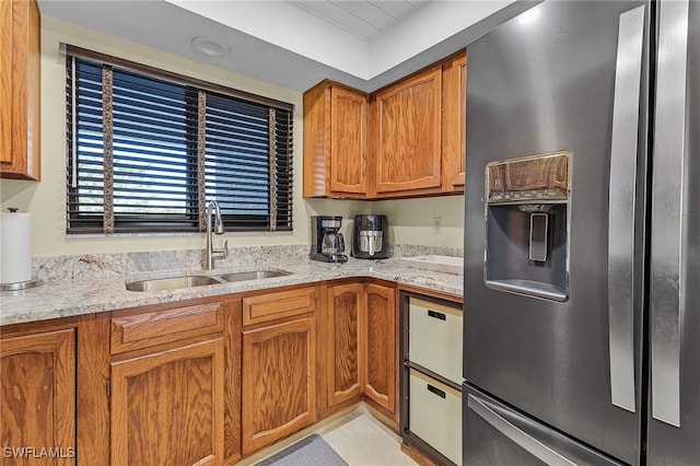 kitchen featuring stainless steel fridge, light stone countertops, sink, and light tile patterned floors