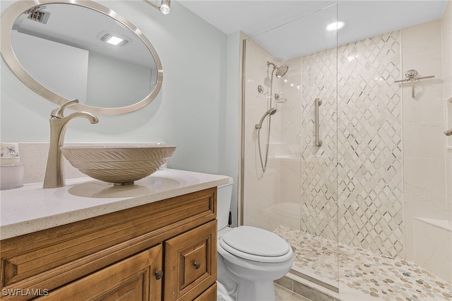 bathroom featuring a tile shower, vanity, and toilet