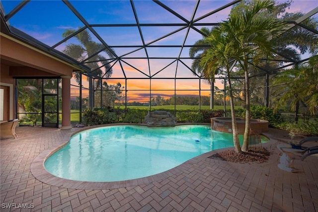 pool at dusk featuring an in ground hot tub, a lanai, and a patio