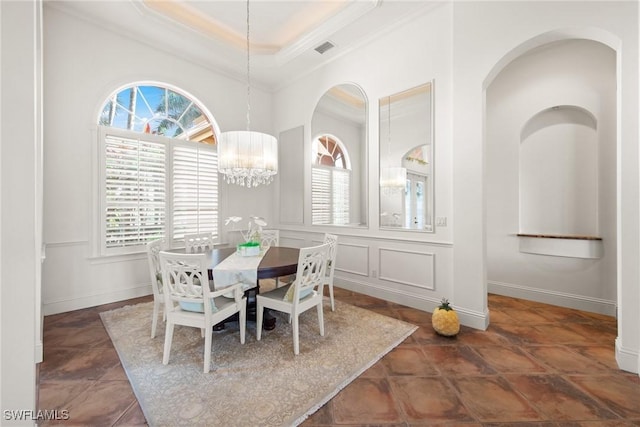 dining space with a notable chandelier, a tray ceiling, and ornamental molding