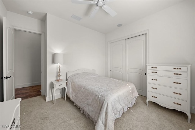 bedroom with ceiling fan, a closet, and light carpet