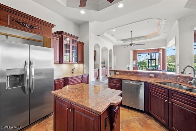 kitchen featuring appliances with stainless steel finishes, a center island, sink, a tray ceiling, and crown molding