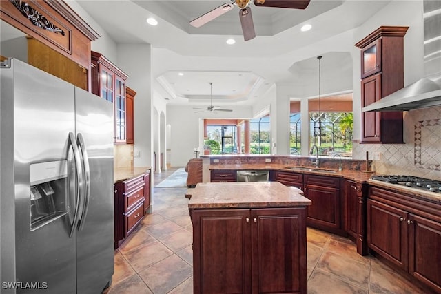 kitchen with a tray ceiling, sink, decorative light fixtures, and appliances with stainless steel finishes