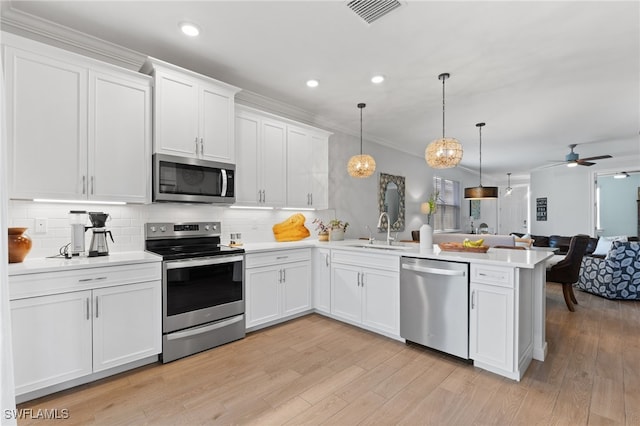 kitchen with stainless steel appliances, white cabinetry, kitchen peninsula, and decorative light fixtures