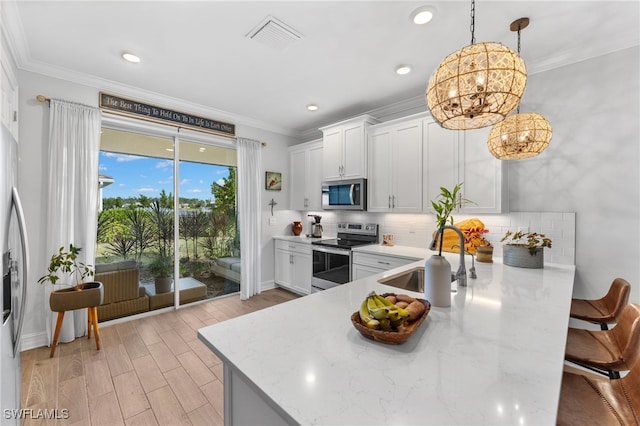 kitchen featuring appliances with stainless steel finishes, decorative light fixtures, sink, and white cabinets