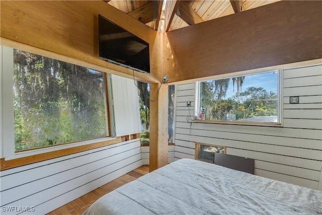 bedroom with wood-type flooring, radiator heating unit, and wood walls