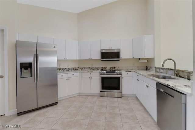 kitchen with sink, stainless steel appliances, white cabinets, and a high ceiling