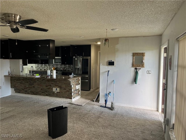 kitchen featuring kitchen peninsula, appliances with stainless steel finishes, tasteful backsplash, light colored carpet, and ceiling fan