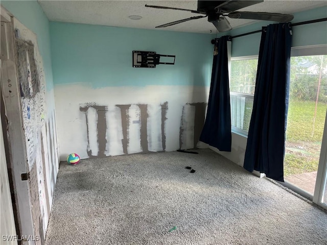 carpeted empty room with ceiling fan and a textured ceiling