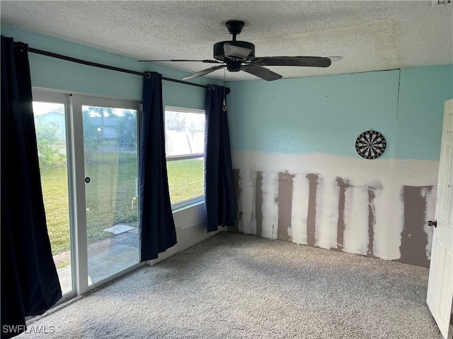 carpeted empty room featuring ceiling fan and a textured ceiling