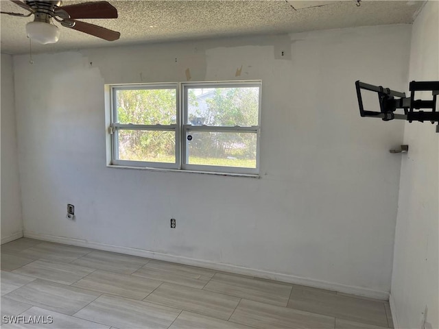 unfurnished room with ceiling fan and a textured ceiling