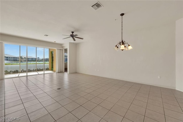 tiled spare room featuring a water view and ceiling fan with notable chandelier